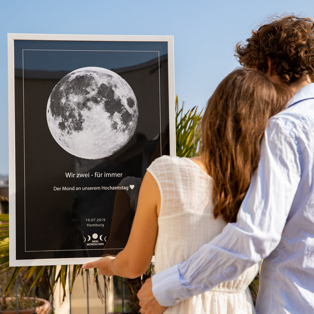 Hochzeitspaar mit einem Mondposter in der Hand